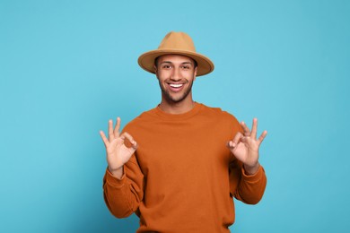 Happy African American man showing ok gesture on light blue background