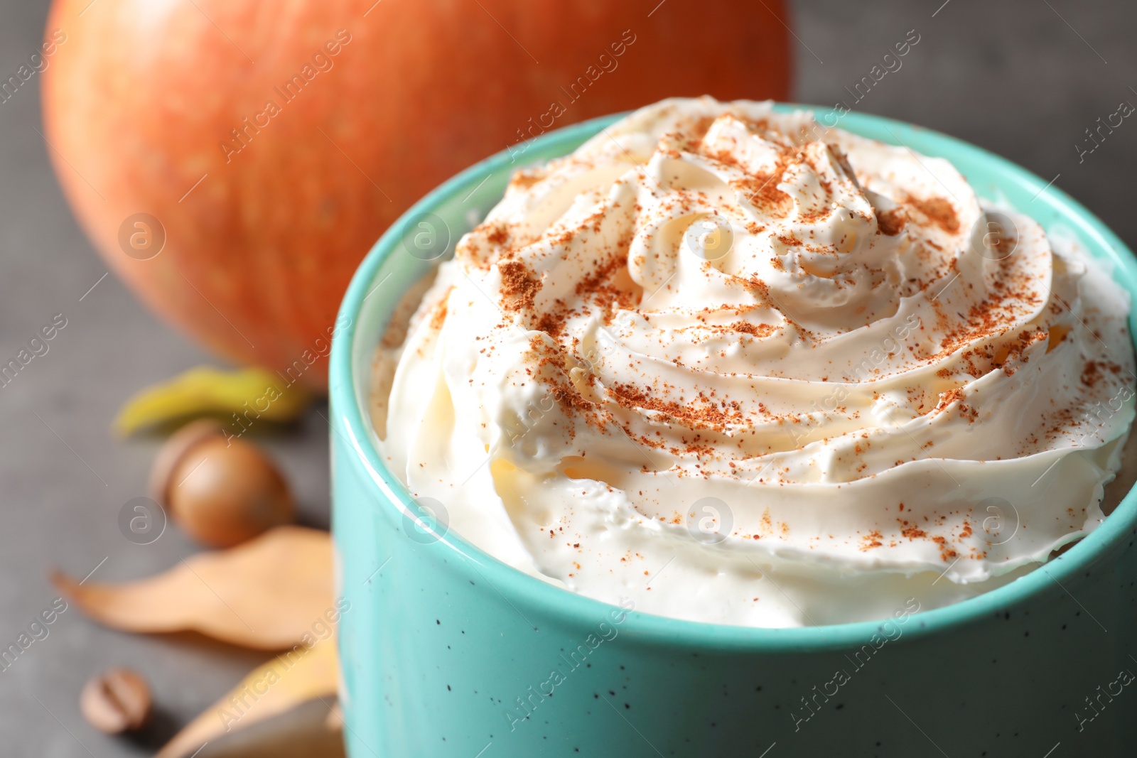 Photo of Cup with pumpkin spice latte on gray table, closeup