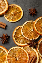 Dry orange slices, cinnamon sticks and anise stars on black table, flat lay