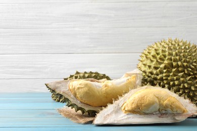 Photo of Fresh ripe durians on light blue wooden table. Space for text
