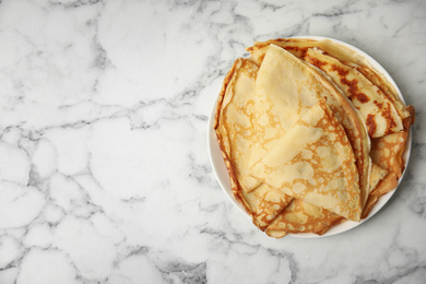 Photo of Stack of fresh thin pancakes on white marble table, top view. Space for text