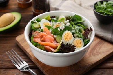 Photo of Delicious salad with boiled eggs, salmon and cheese in bowl on wooden table, closeup