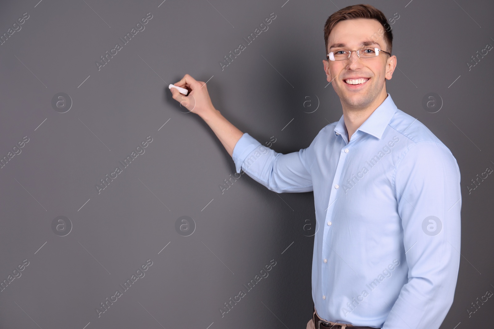 Photo of Young male teacher with chalk on grey background