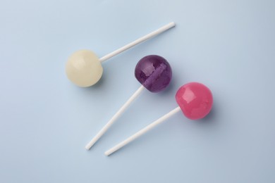 Tasty lollipops on light blue background, flat lay