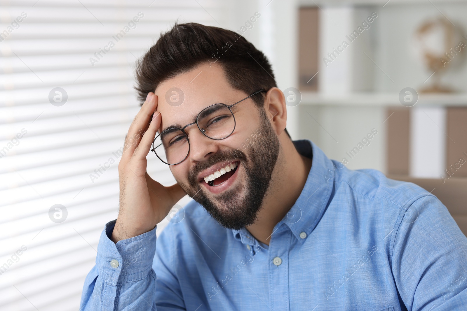 Photo of Portrait of handsome young man laughing in office