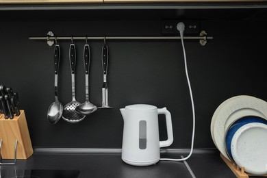 Electric kettle and kitchen utensils on black countertop