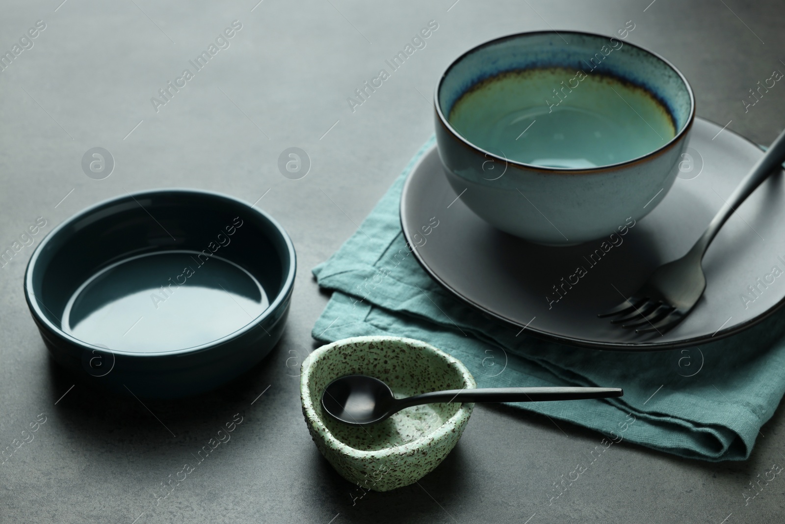 Photo of Set of stylish empty dishware and cutlery on grey table