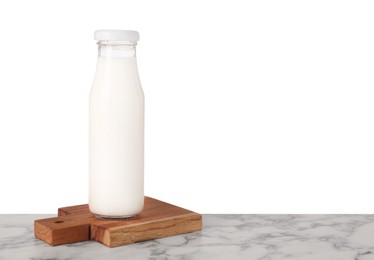 Photo of Bottle with tasty milk and wooden board on marble table against white background