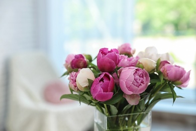 Photo of Vase with bouquet of beautiful peonies in room, space for text