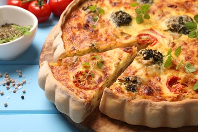 Delicious homemade vegetable quiche on light blue table, closeup