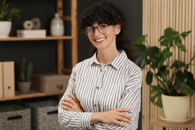 Portrait of beautiful woman with curly hair indoors. Attractive lady smiling and looking into camera