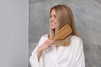 Photo of Beautiful woman brushing her hair in bathroom