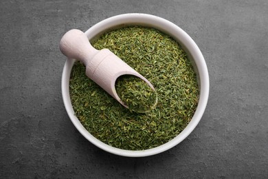 Bowl and scoop with dried thyme on grey table, top view