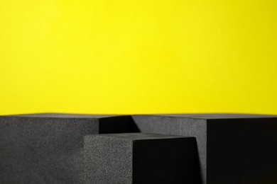 Photo of Many black geometric figures on yellow background, closeup with space for text. Stylish presentation for product