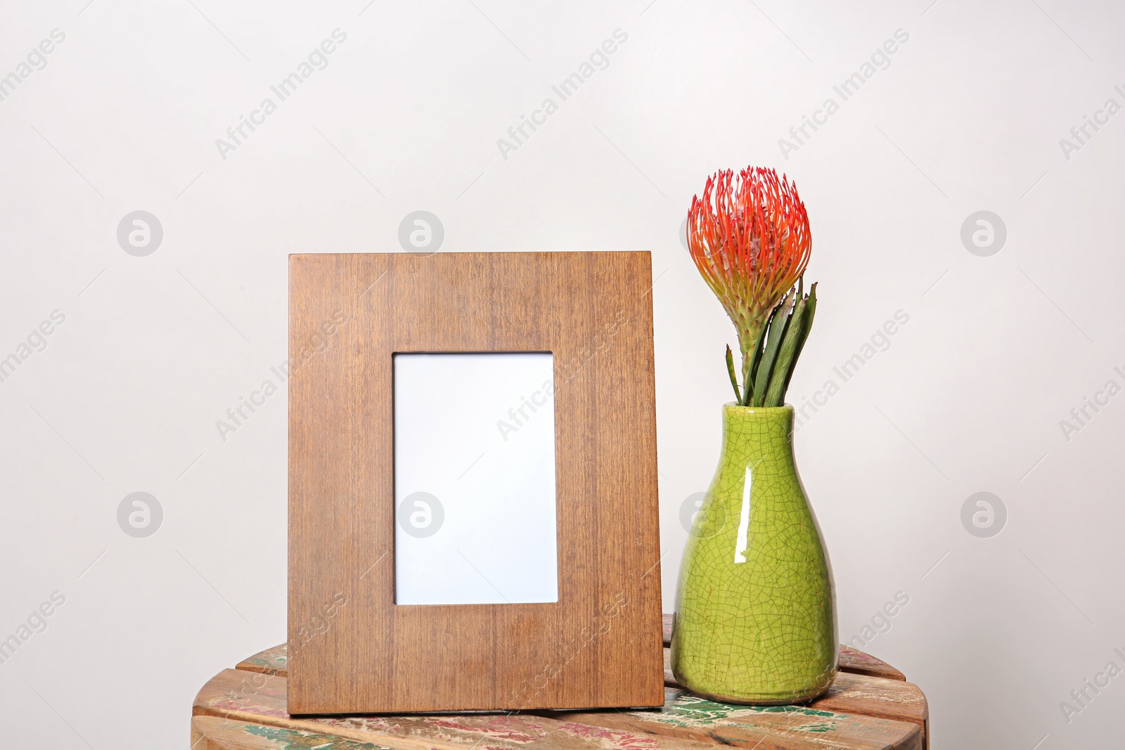 Photo of Blank frame and vase with flower on table against white background. Mock up for design