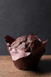 Photo of Tasty chocolate muffin on wooden table, closeup. Space for text