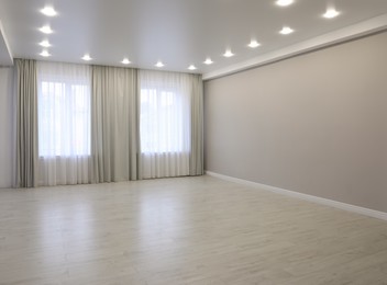 Empty room with beige wall, large window and wooden floor