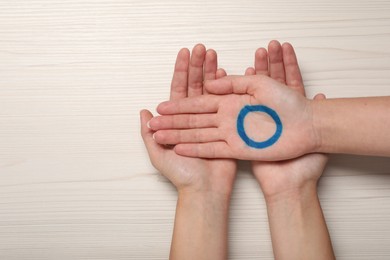 People showing blue circle as World Diabetes Day symbol at white wooden table, top view with space for text