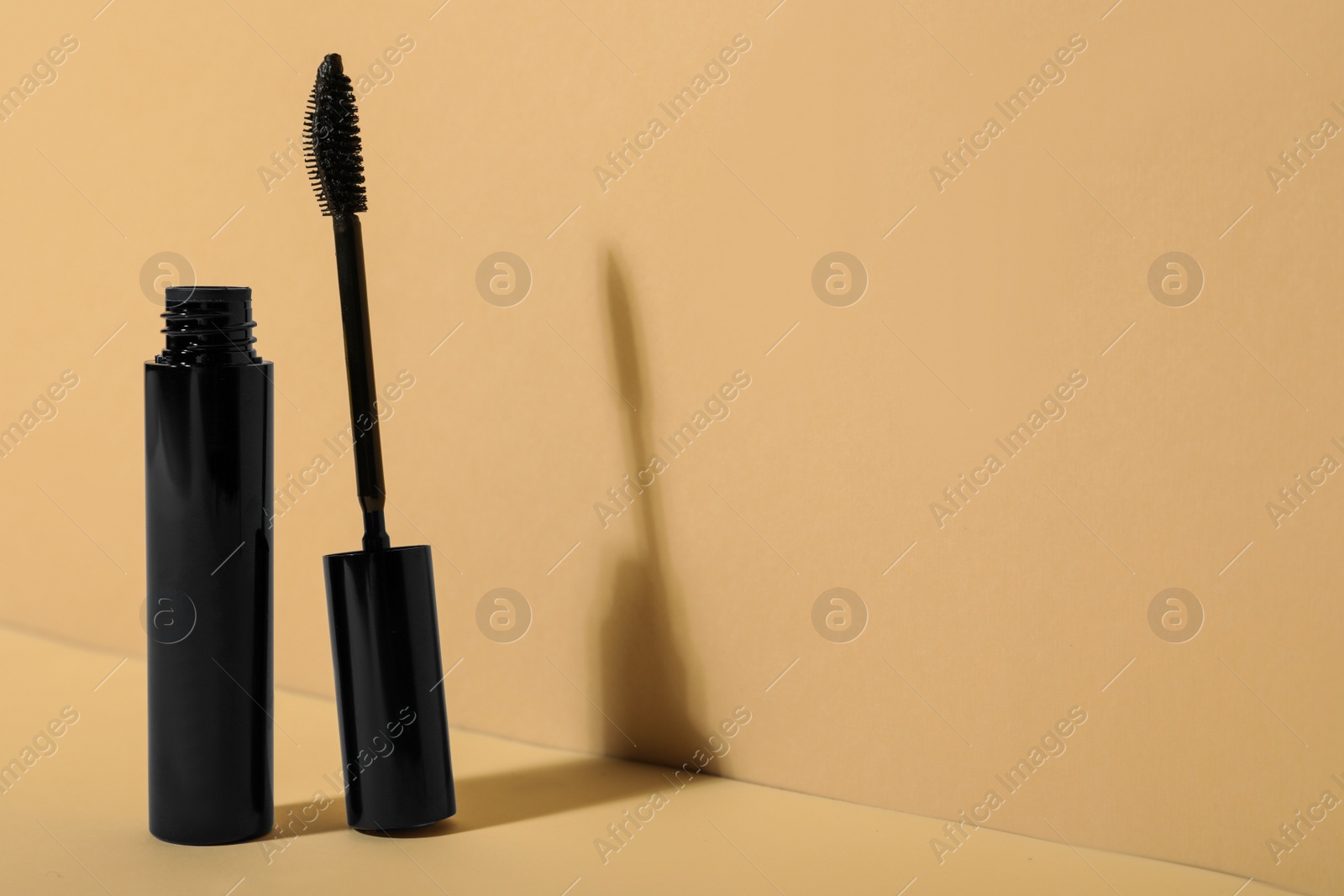 Photo of Mascara on beige background, space for text. Makeup product