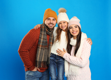 Photo of Happy family in warm clothes on blue background. Winter vacation