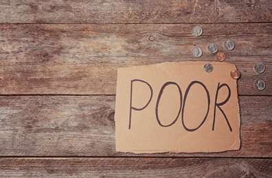 Photo of Carton sign with word POOR and space for text on wooden background, top view