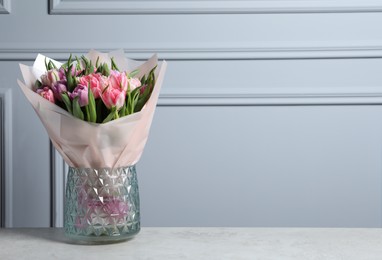 Photo of Vase with bouquet of beautiful tulips on grey table. Space for text