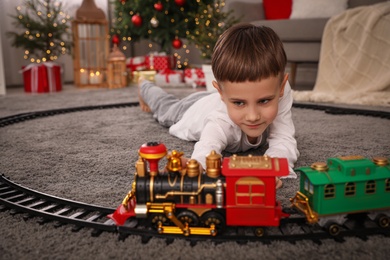 Little boy playing with colorful train toy in room decorated for Christmas