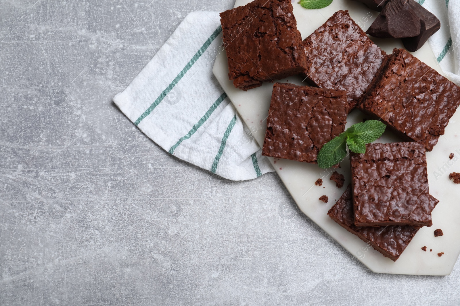 Photo of Delicious chocolate brownies with fresh mint on grey table, top view. Space for text