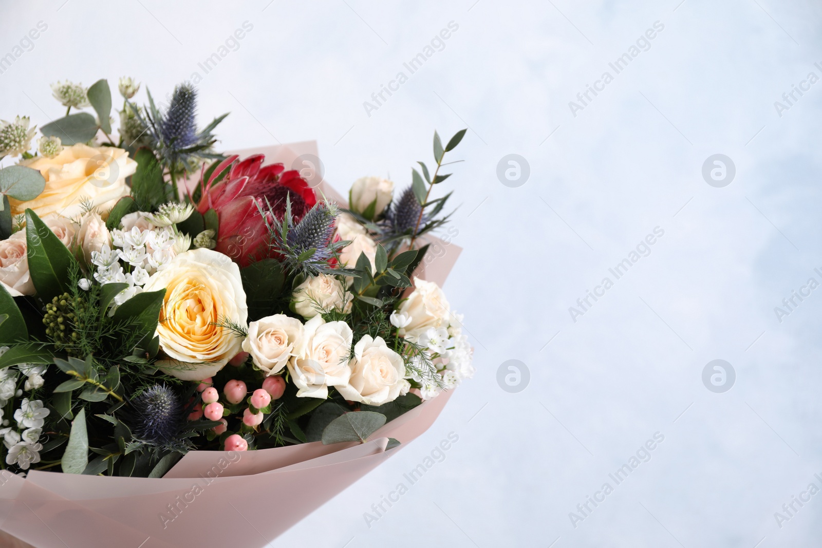 Photo of Beautiful bouquet with roses on light blue background. Space for text