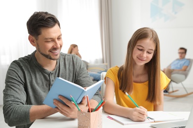 Father helping his teenager daughter with homework indoors