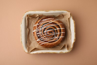 Photo of Delicious roll with topping and poppy seeds on beige table, top view. Sweet bun