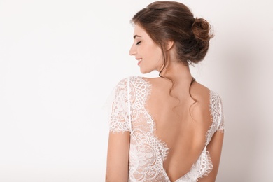 Photo of Young bride wearing beautiful wedding dress on light background