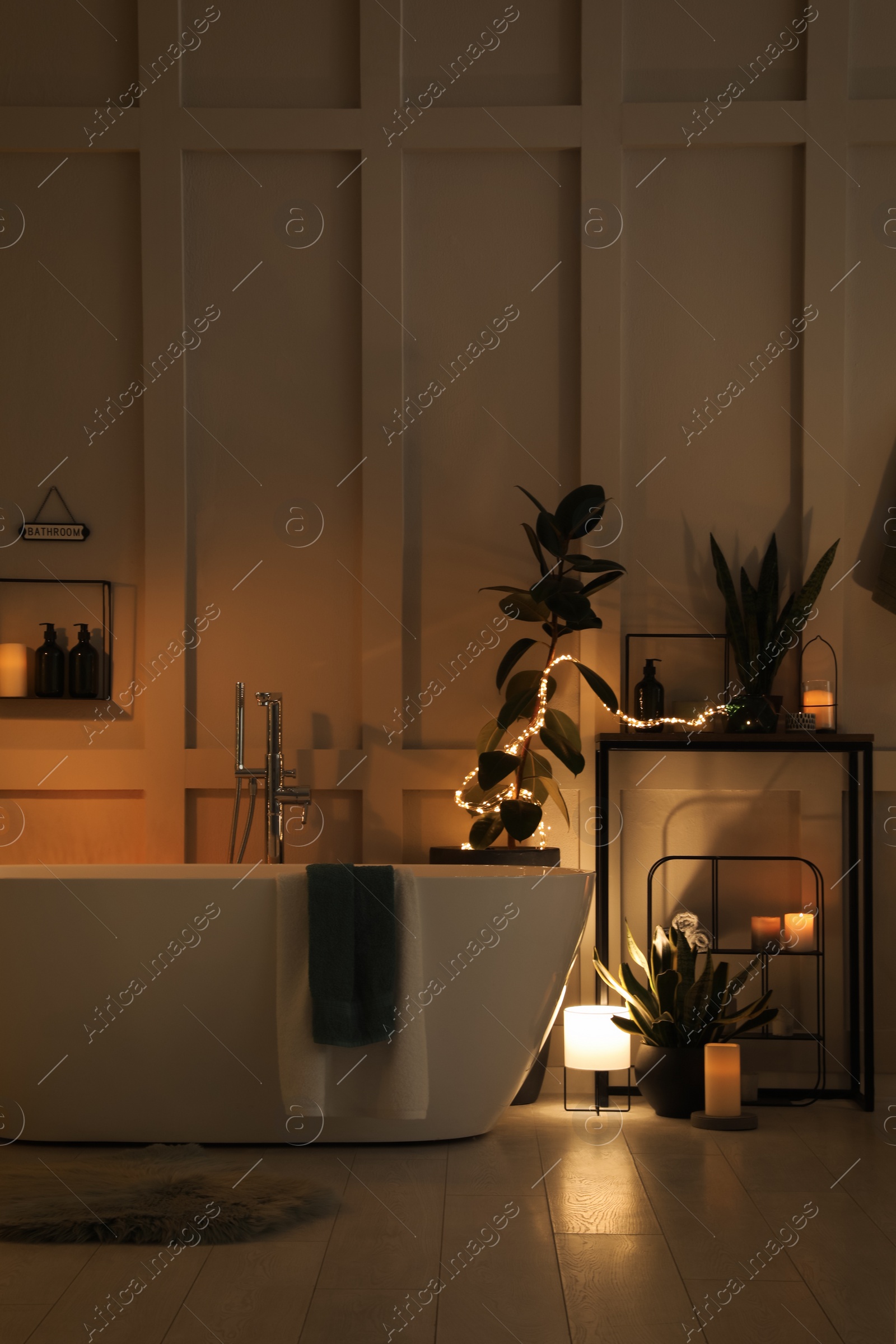 Photo of Stylish bathroom interior with houseplants and string lights. Home design