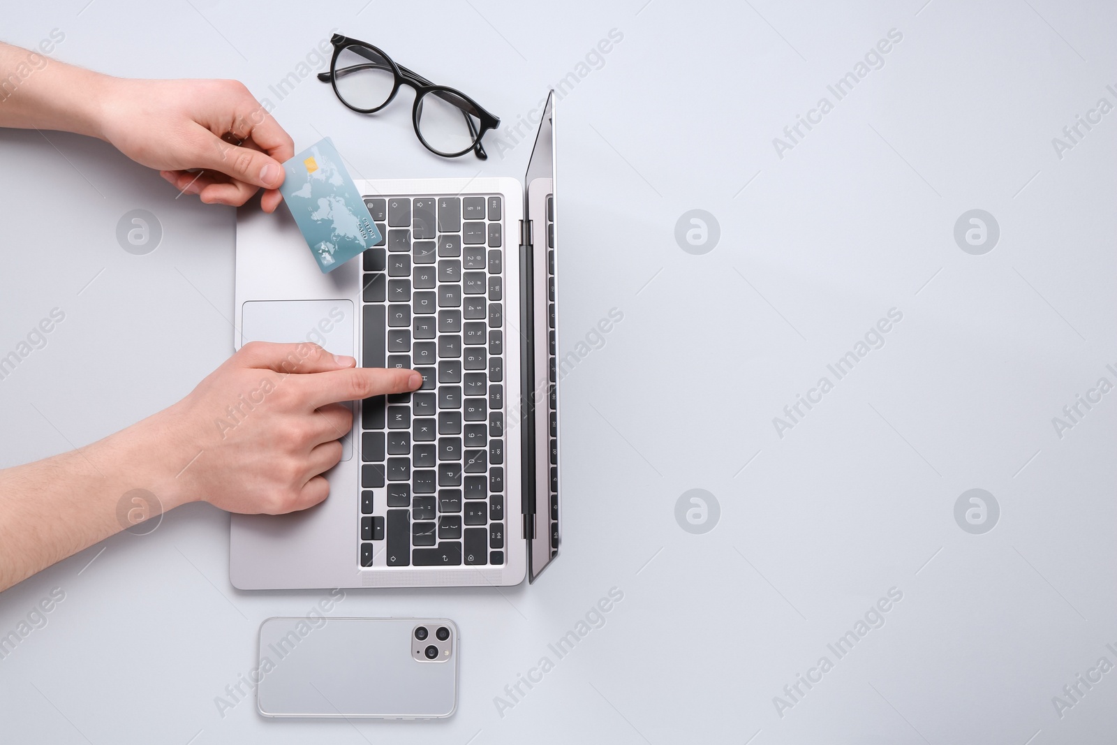 Photo of Online payment. Man with laptop, smartphone and credit card on light grey background, top view. Space for text