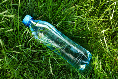 Photo of Bottle of fresh water on green grass, top view