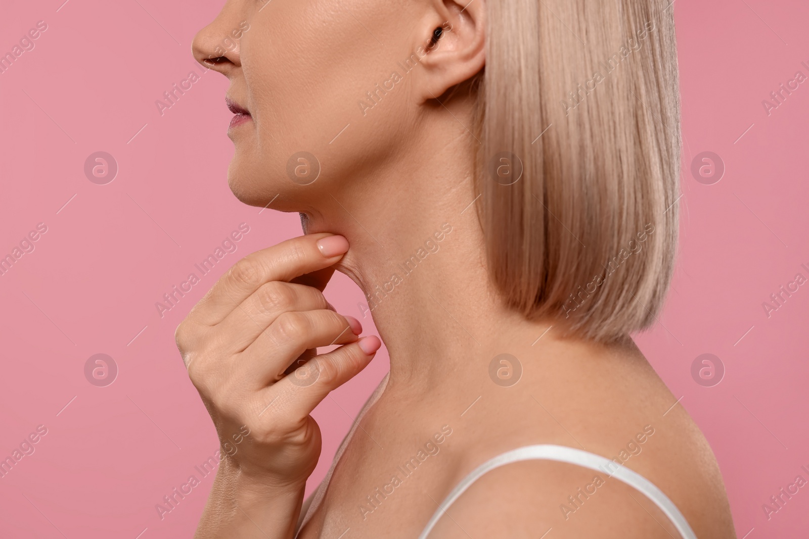 Photo of Woman touching her neck on pink background, closeup