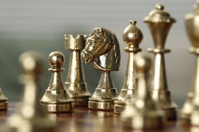 Photo of Golden knight and other chess pieces on game board, closeup