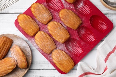 Delicious madeleine cookies and baking mold on white wooden table, flat lay