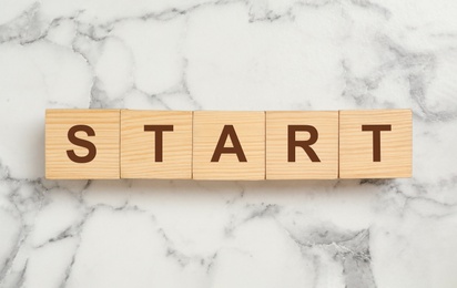 Photo of Word START made with wooden cubes on white marble background, flat lay