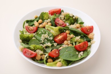 Photo of Healthy meal. Tasty salad with quinoa, chickpeas and vegetables on beige table, closeup