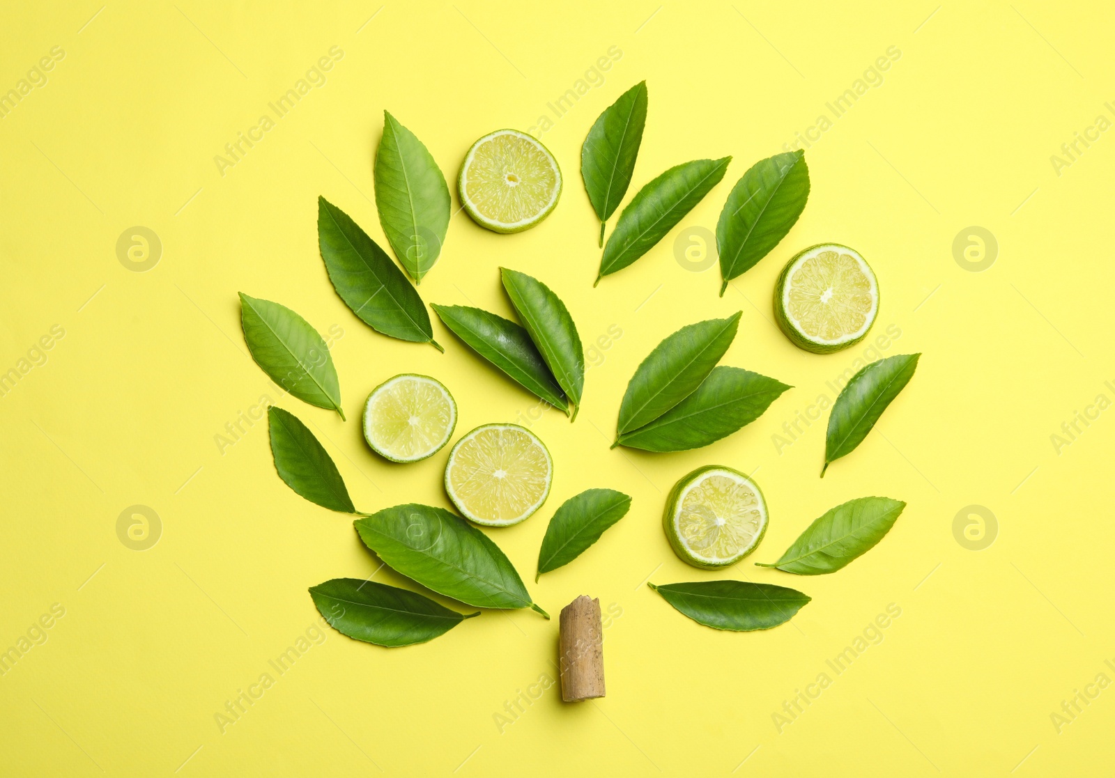 Photo of Flat lay composition with fresh green citrus leaves and lime slices on yellow background