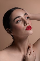 Photo of Portrait of beautiful young woman with red lips on brown background, closeup