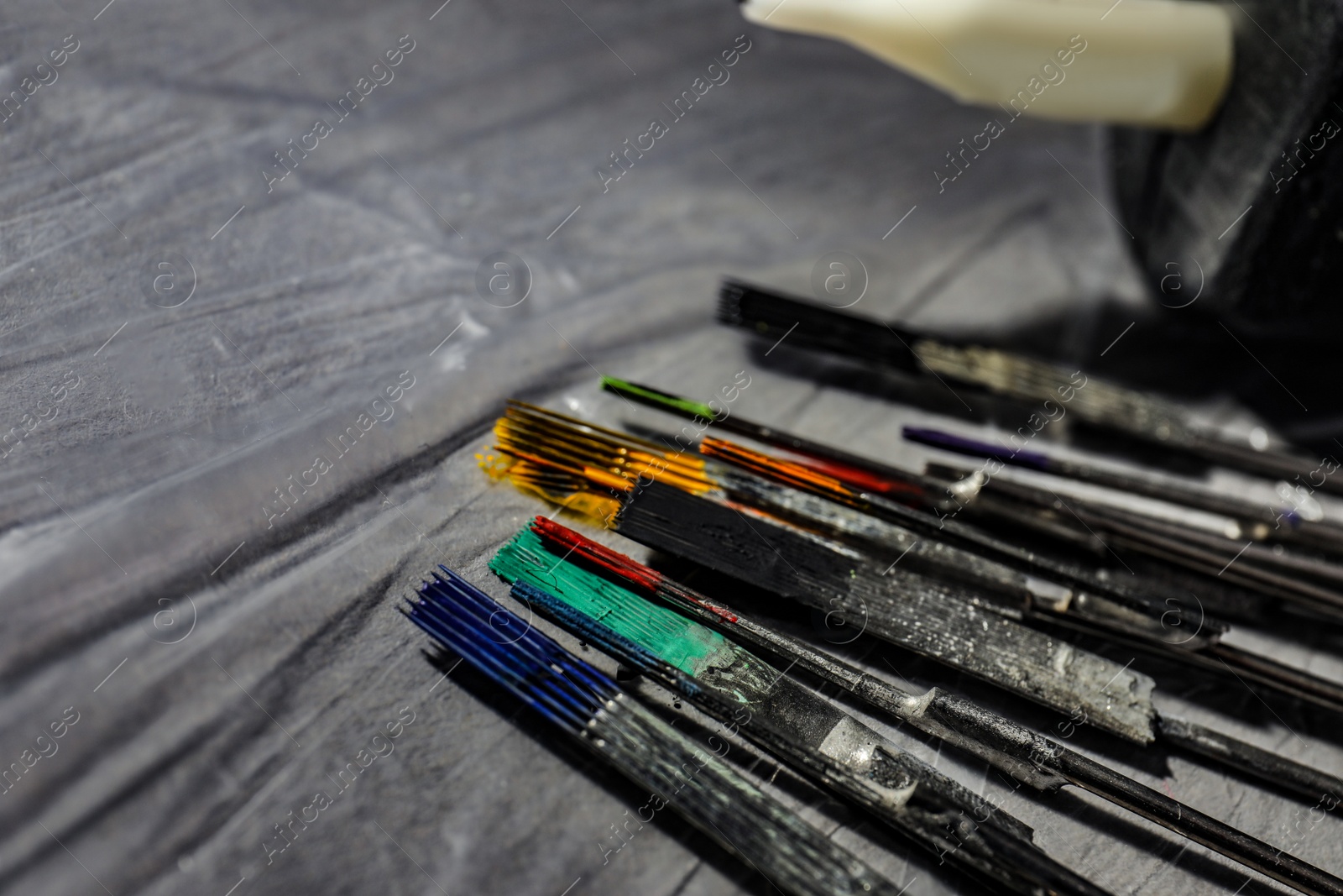 Photo of Tattoo needles covered with colorful inks on table, closeup. Space for text