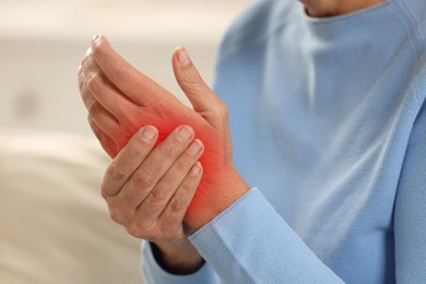 Woman suffering from pain in wrist indoors, closeup