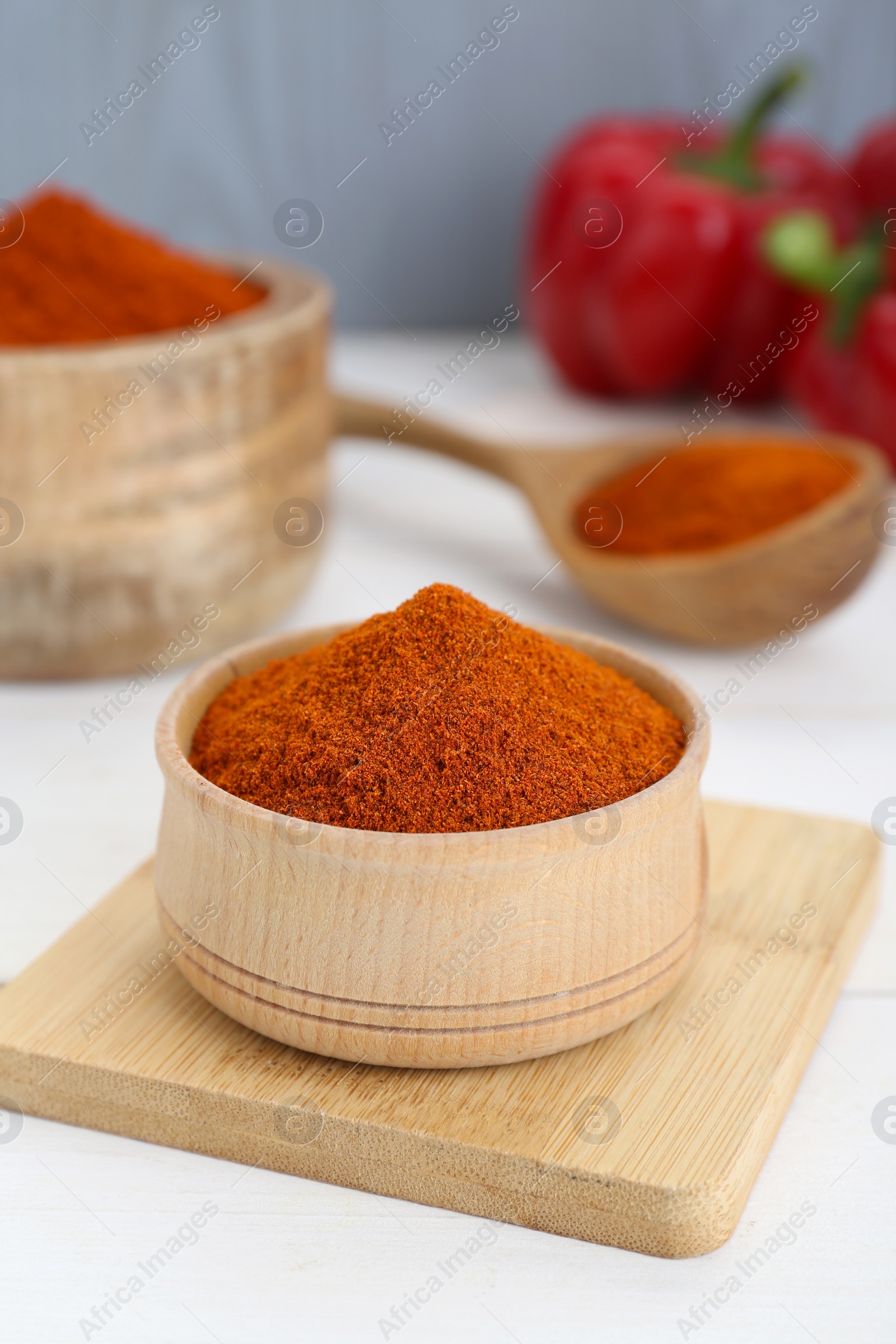 Photo of Bowls and spoon with aromatic paprika powder on white table