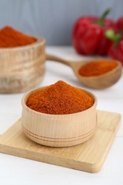 Bowls and spoon with aromatic paprika powder on white table