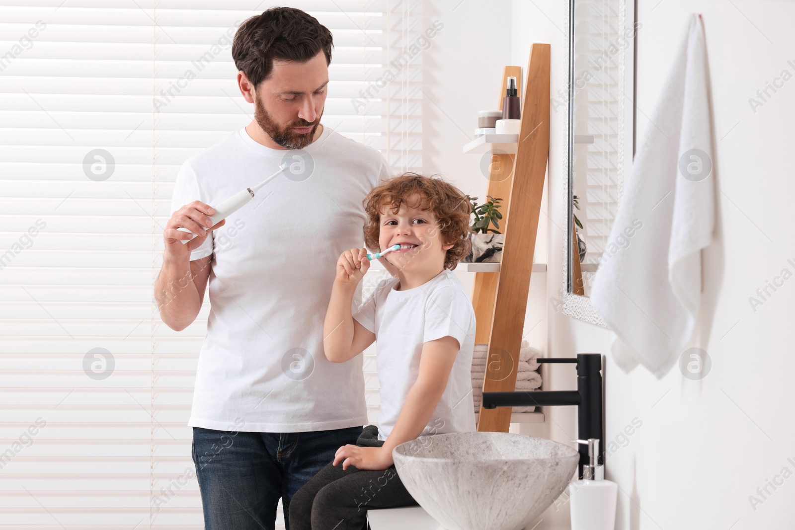 Photo of Father and his son brushing teeth together in bathroom