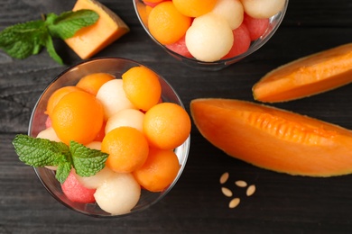 Melon and watermelon balls on black wooden table, flat lay