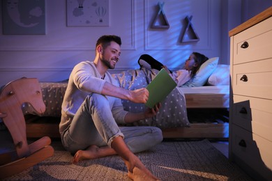 Photo of Father reading bedtime story to his daughter at home