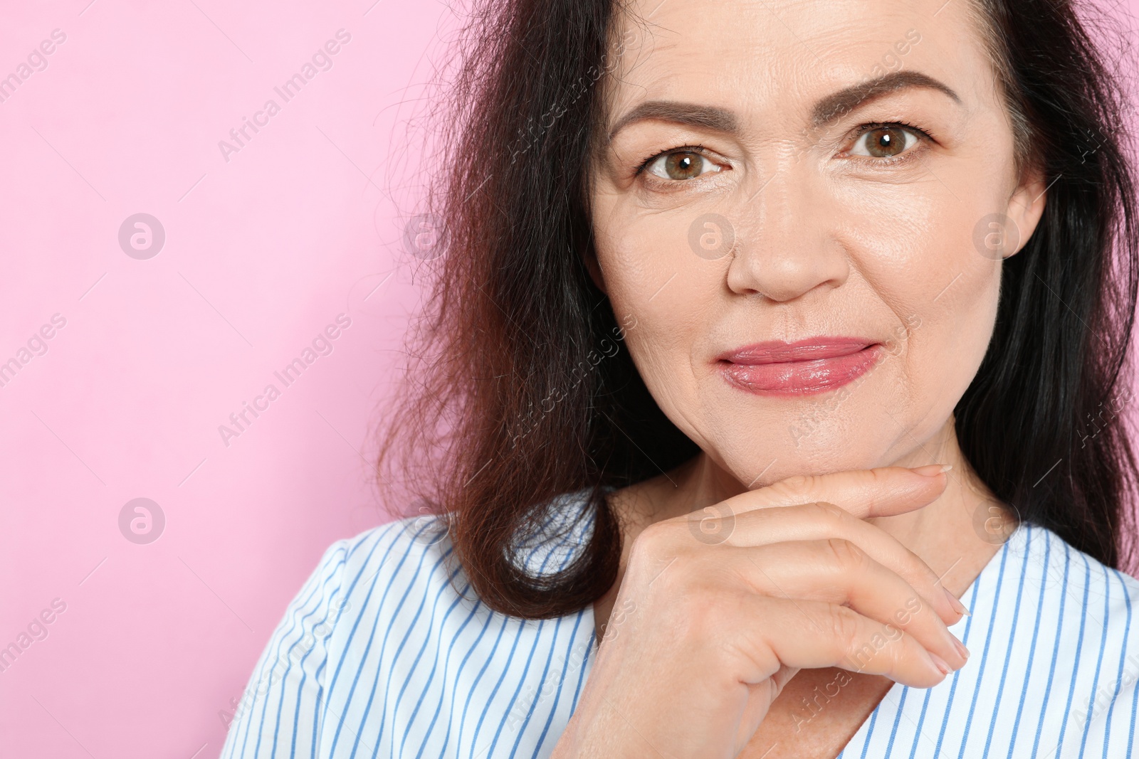 Photo of Portrait of mature woman with beautiful face on pink background